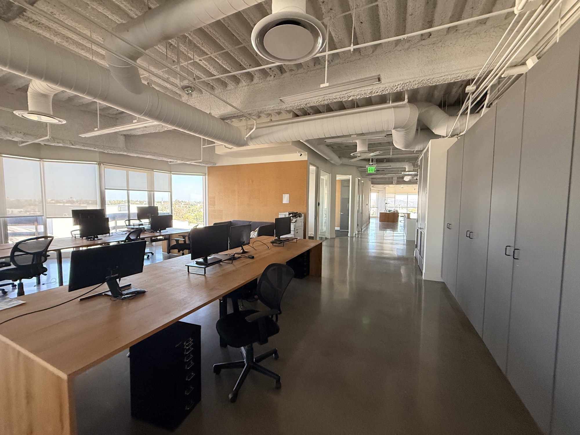Long desk rows with monitors and wraparound windows over Los Angeles
