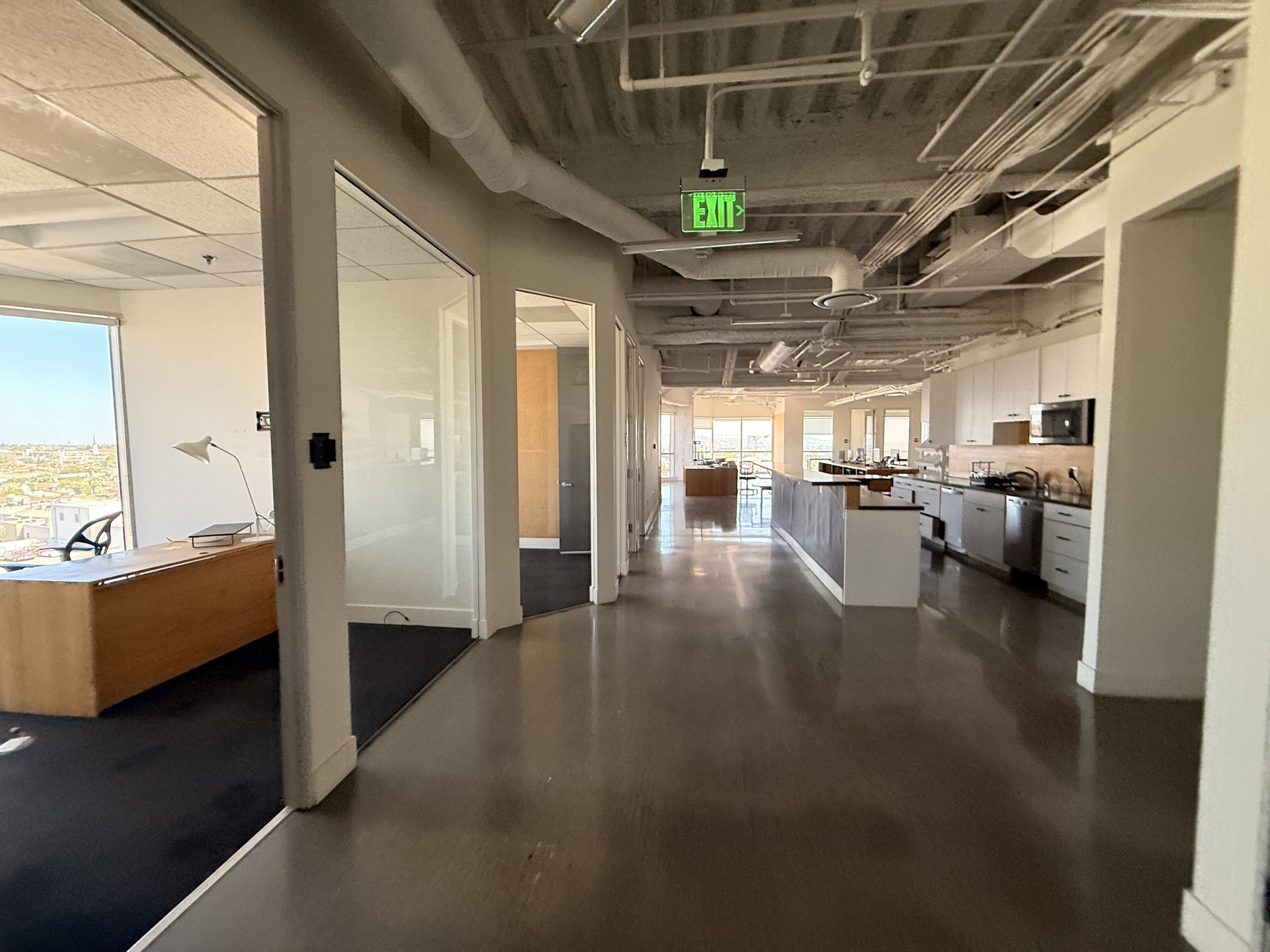 Hallway with glass-walled private offices and city views